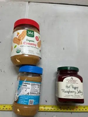two jars of peanut butter and one jar of hot pepper raspberry jelly